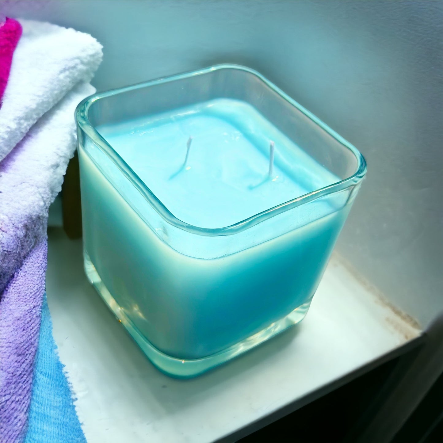 April Fresh Downy Triple Scented Candle blue candle with colorful towels